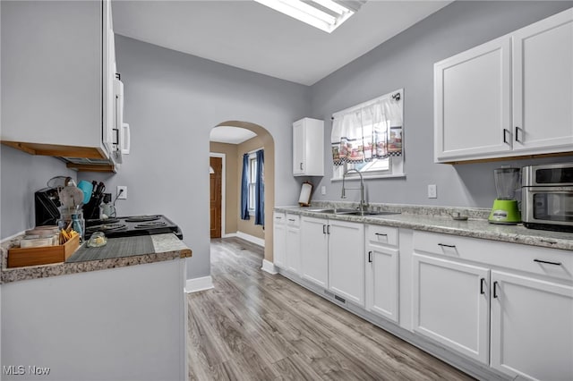 4532 W 172nd St, Cleveland, OH 44135 - kitchen featuring arched walkways, white cabinets, light wood-style floors, and electric stove