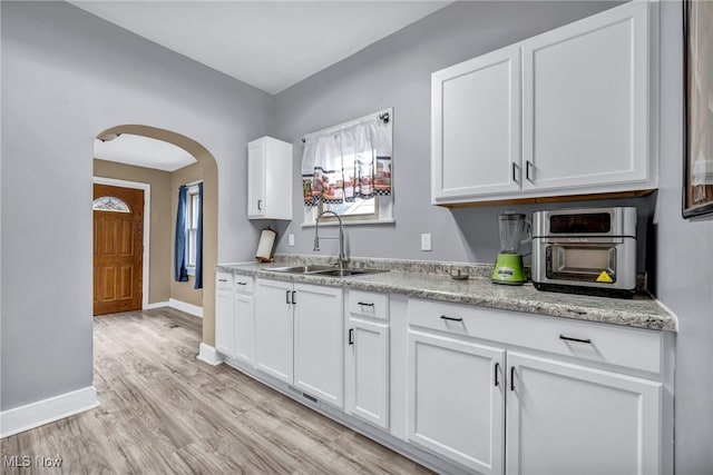 4532 W 172nd St, Cleveland, OH 44135 - kitchen featuring arched walkways, white cabinets, light wood-style flooring, and light stone countertops