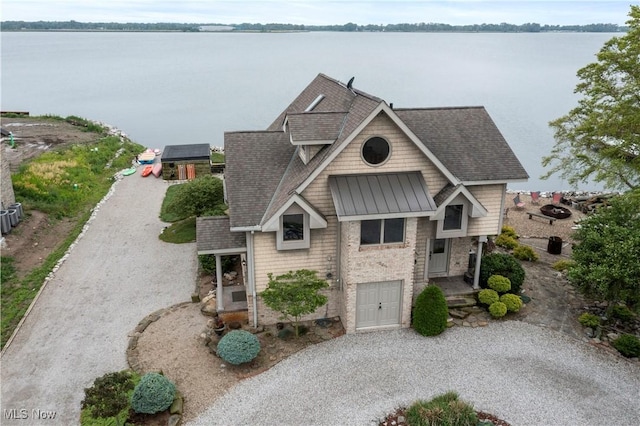 731 Cedar Point Rd, Sandusky, OH 44870 - view of front of house featuring gravel driveway, a standing seam roof, a shingled roof, a water view, and an attached garage