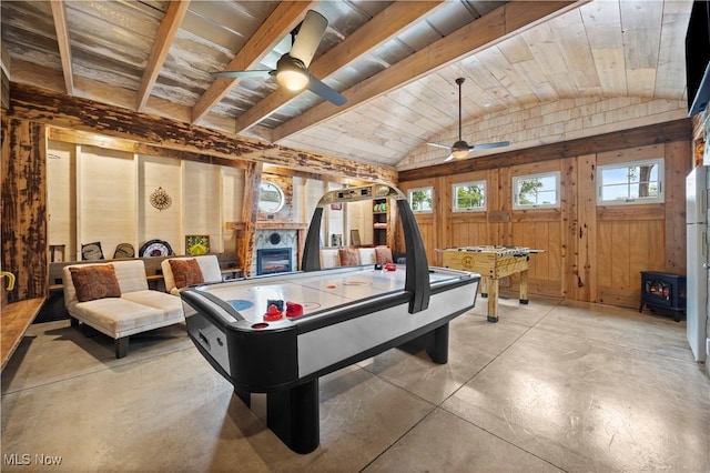 731 Cedar Point Rd, Sandusky, OH 44870 - game room featuring a ceiling fan, vaulted ceiling, a wood stove, concrete floors, and wood walls