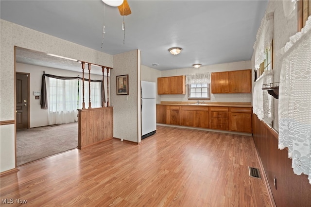 2100 Priscilla Ave NW, Massillon, OH 44647 - kitchen with freestanding refrigerator, brown cabinetry, light wood-style floors, and light countertops