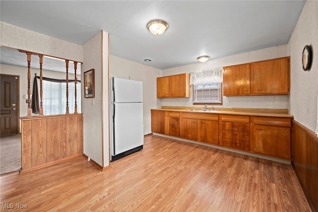 2100 Priscilla Ave NW, Massillon, OH 44647 - kitchen with freestanding refrigerator, brown cabinets, light wood-style flooring, and light countertops