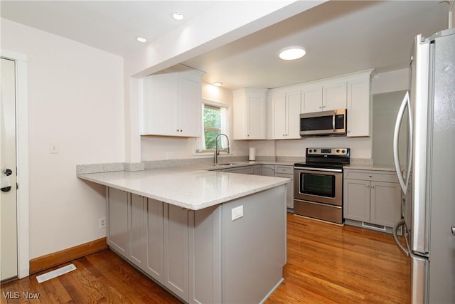 260 Morgan, Oberlin, OH 44074 - kitchen featuring appliances with stainless steel finishes, a peninsula, light wood-style floors, white cabinets, and a breakfast bar area
