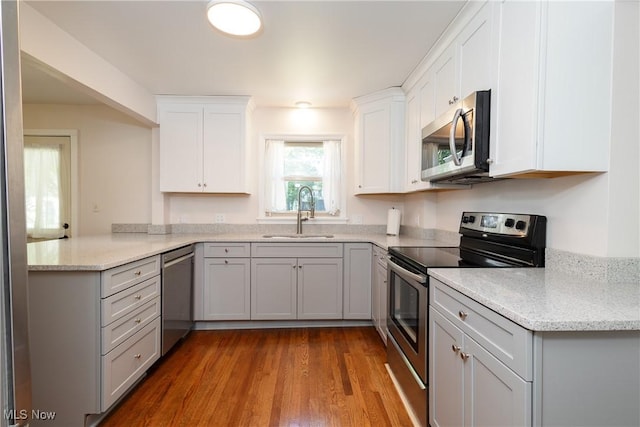 260 Morgan, Oberlin, OH 44074 - kitchen featuring stainless steel appliances, a peninsula, wood finished floors, white cabinets, and light stone countertops