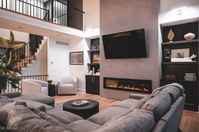 7363 Kempton Ct, Canfield, OH 44406 - living room featuring wood finished floors, built in features, a fireplace, a towering ceiling, and stairs