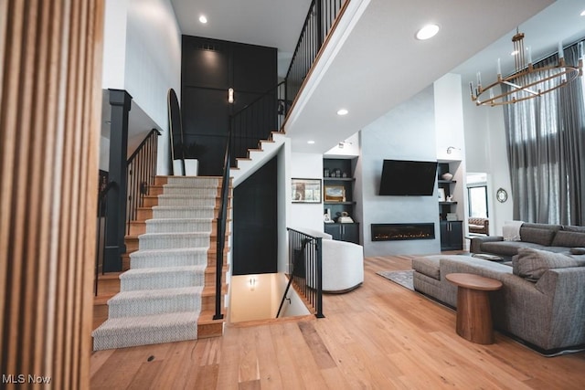 7363 Kempton Ct, Canfield, OH 44406 - living area with a towering ceiling, hardwood / wood-style floors, a chandelier, a glass covered fireplace, and stairway