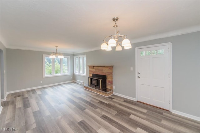 6114 Crossview Rd, Seven Hills, OH 44131 - unfurnished living room with a chandelier, plenty of natural light, light wood-type flooring, ornamental molding, and a stone fireplace
