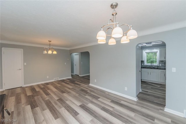 6114 Crossview Rd, Seven Hills, OH 44131 - spare room featuring arched walkways, a chandelier, and light wood-type flooring