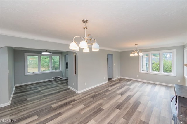 6114 Crossview Rd, Seven Hills, OH 44131 - unfurnished living room featuring a chandelier, arched walkways, and wood finished floors