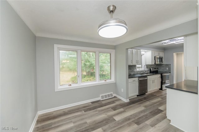 6114 Crossview Rd, Seven Hills, OH 44131 - kitchen featuring stainless steel appliances, dark countertops, backsplash, wood finished floors, and white cabinetry