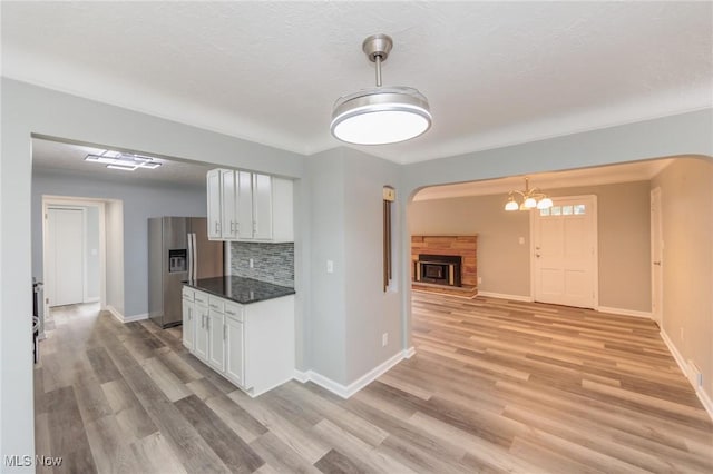 6114 Crossview Rd, Seven Hills, OH 44131 - kitchen featuring stainless steel fridge with ice dispenser, white cabinetry, a fireplace with raised hearth, and light wood-type flooring