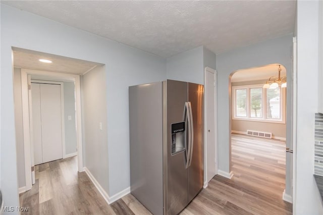 6114 Crossview Rd, Seven Hills, OH 44131 - kitchen featuring stainless steel refrigerator with ice dispenser, light wood-type flooring, arched walkways, a chandelier, and a textured ceiling