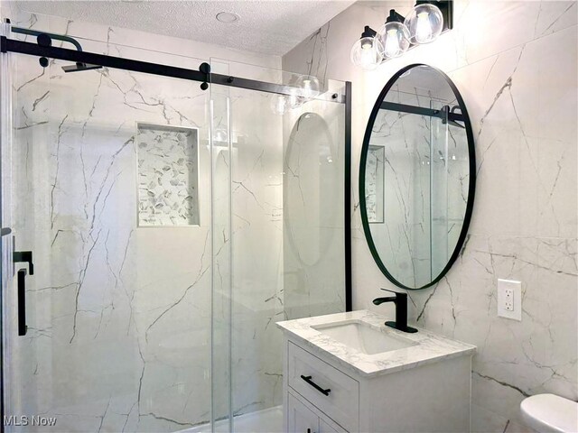 2337 Charney Rd, University Heights, OH 44118 - full bath featuring vanity, a marble finish shower, a textured ceiling, and tile walls