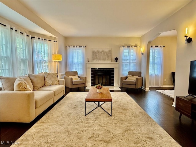 2337 Charney Rd, University Heights, OH 44118 - living room featuring healthy amount of natural light, dark wood-style floors, arched walkways, and a tiled fireplace