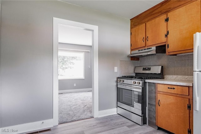 3606 Liberty St, Parkersburg, WV 26104 - kitchen with stainless steel range with gas cooktop, under cabinet range hood, light countertops, decorative backsplash, and brown cabinets