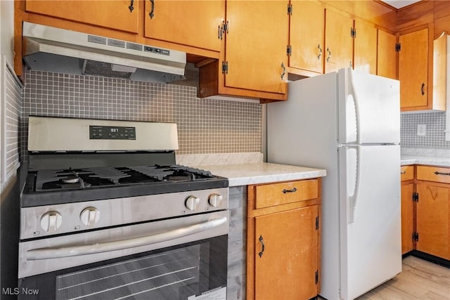 3606 Liberty St, Parkersburg, WV 26104 - kitchen with stainless steel gas range, under cabinet range hood, freestanding refrigerator, decorative backsplash, and light countertops