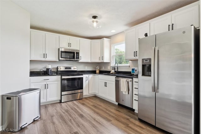 3523 Magnolia Dr, Lorain, OH 44053 - kitchen with stainless steel appliances, dark countertops, white cabinets, light wood finished floors, and recessed lighting