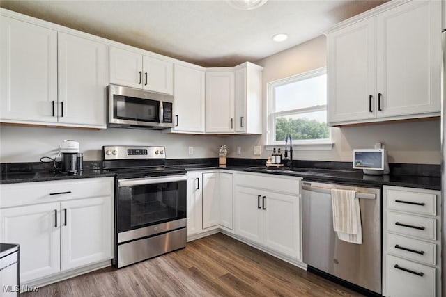 3523 Magnolia Dr, Lorain, OH 44053 - kitchen featuring stainless steel appliances, white cabinetry, wood finished floors, recessed lighting, and dark countertops