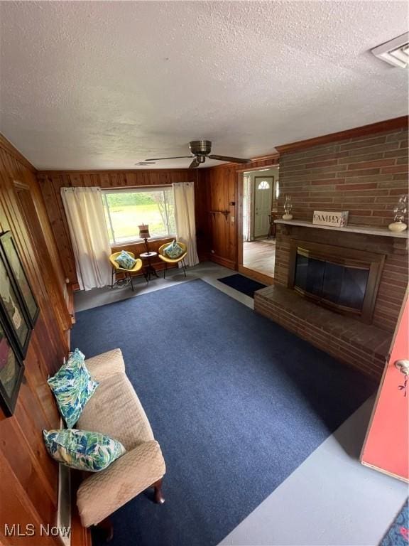 1781 Pleasant Valley Rd, Girard, OH 44420 - living area with a textured ceiling, wood walls, a ceiling fan, and a fireplace