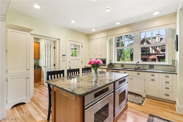 2820 W Park Blvd, Shaker Heights, OH 44120 - kitchen featuring a kitchen bar, light wood finished floors, tasteful backsplash, dark stone counters, and recessed lighting