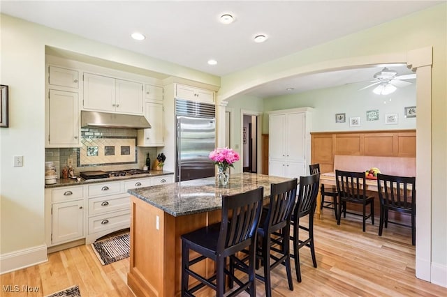 2820 W Park Blvd, Shaker Heights, OH 44120 - kitchen with stainless steel appliances, under cabinet range hood, ceiling fan, arched walkways, and dark stone counters