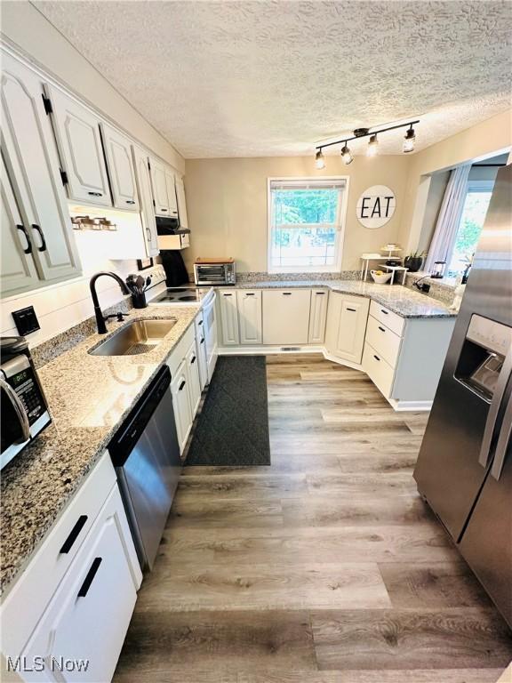 132 Dennis Dr, Cortland, OH 44410 - kitchen with dishwasher, light wood-style flooring, rail lighting, white cabinetry, and exhaust hood