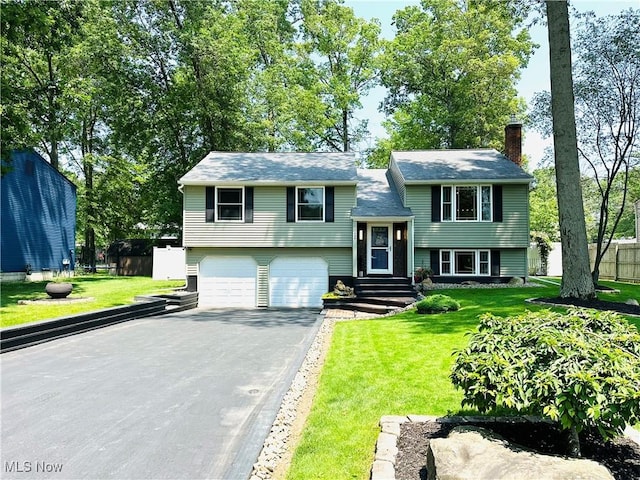 132 Dennis Dr, Cortland, OH 44410 - bi-level home featuring asphalt driveway, an attached garage, and a chimney