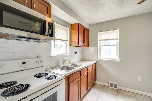 640 E 261st St, Euclid, OH 44132 - kitchen with white range with electric stovetop, stainless steel microwave, light countertops, backsplash, and brown cabinetry