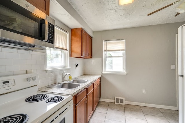 640 E 261st St, Euclid, OH 44132 - kitchen featuring electric range, stainless steel microwave, brown cabinets, decorative backsplash, and light countertops