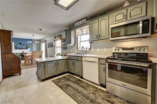 5075 State Route 250 NW, Beach City, OH 44608 - kitchen featuring appliances with stainless steel finishes, a peninsula, light countertops, a chandelier, and gray cabinetry