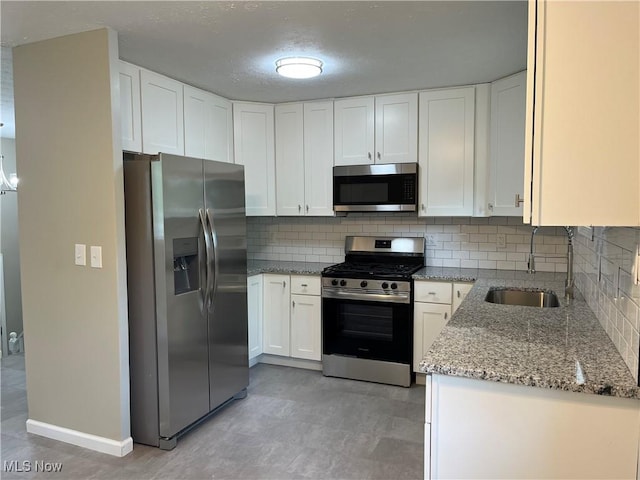 5482 Pleasant St, North Ridgeville, OH 44039 - kitchen with stainless steel appliances, light stone countertops, white cabinets, and decorative backsplash