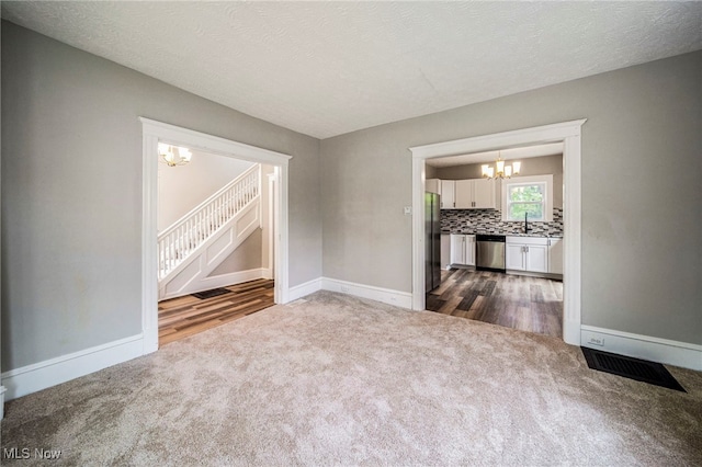 1115 W 43rd St, Ashtabula, OH 44004 - empty room featuring a chandelier, dark carpet, stairway, and dark wood finished floors