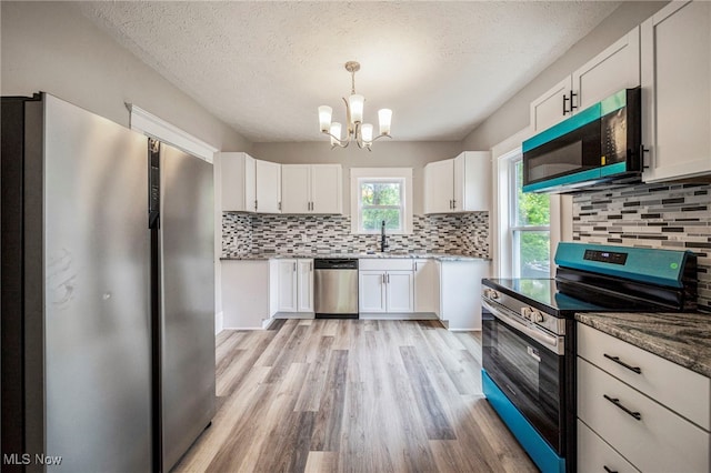 1115 W 43rd St, Ashtabula, OH 44004 - kitchen with appliances with stainless steel finishes, a chandelier, light wood-style flooring, white cabinetry, and backsplash