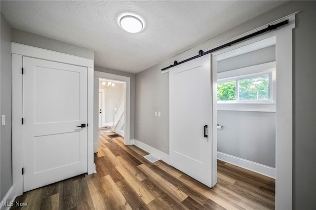 1115 W 43rd St, Ashtabula, OH 44004 - corridor featuring a barn door, wood finished floors, a textured ceiling, and stairway