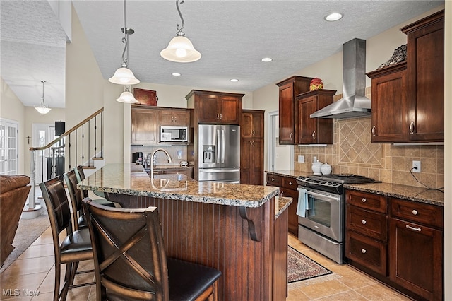 34782 Legends Way, Grafton, OH 44044 - kitchen with appliances with stainless steel finishes, ventilation hood, tasteful backsplash, a breakfast bar, and a textured ceiling
