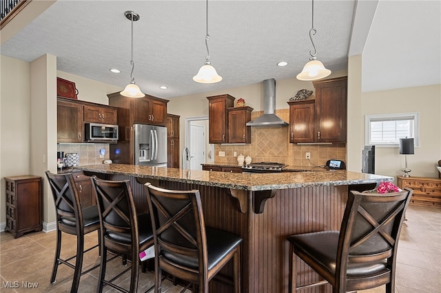 34782 Legends Way, Grafton, OH 44044 - kitchen with wall chimney range hood, stainless steel appliances, stone countertops, tasteful backsplash, and a breakfast bar area