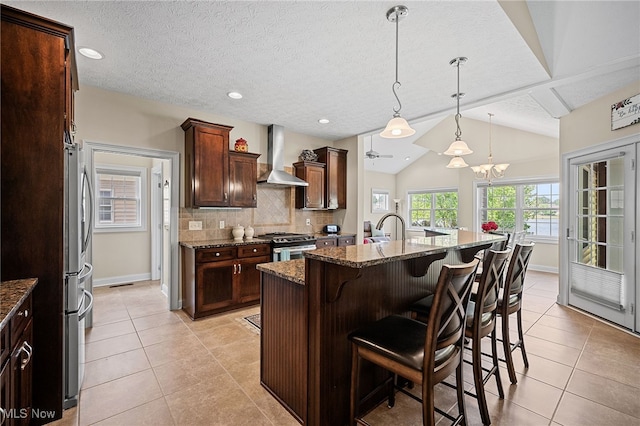 34782 Legends Way, Grafton, OH 44044 - kitchen with wall chimney range hood, light tile patterned flooring, a breakfast bar area, dark stone countertops, and stainless steel appliances