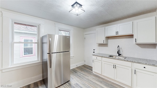 1851 W 52nd St, Cleveland, OH 44102 - kitchen featuring freestanding refrigerator, light wood-style floors, light stone counters, and white cabinets