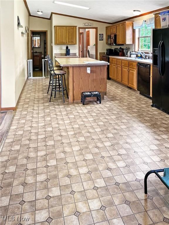 4182 Reger Rd, Conneaut, OH 44030 - kitchen with black appliances, washer / dryer, crown molding, light countertops, and a center island