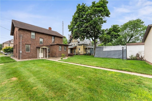 119 5th St SW, Strasburg, OH 44680 - back of property featuring a chimney, brick siding, and a yard