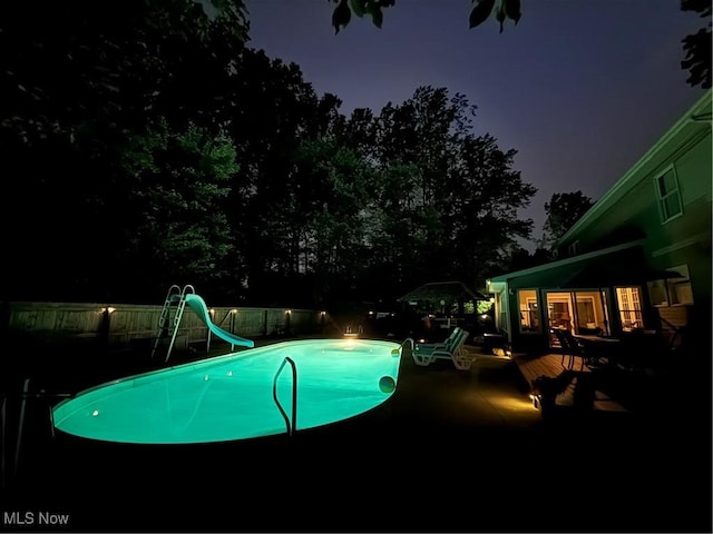 449 Westchester Dr SE, Warren, OH 44484 - pool at night with a water slide and a wooden deck