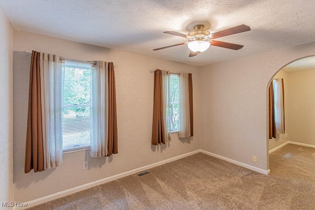 449 Westchester Dr SE, Warren, OH 44484 - empty room with arched walkways, plenty of natural light, a textured ceiling, a ceiling fan, and carpet