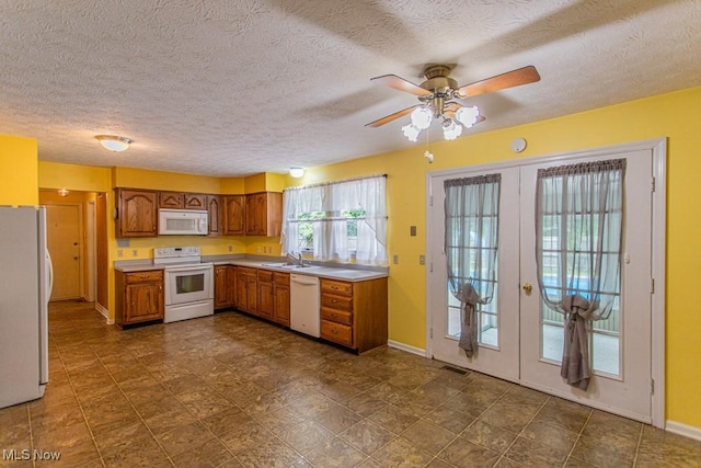 449 Westchester Dr SE, Warren, OH 44484 - kitchen with white appliances, brown cabinetry, french doors, ceiling fan, and light countertops