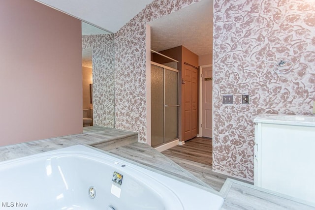 449 Westchester Dr SE, Warren, OH 44484 - full bath with wallpapered walls, wood finished floors, a shower stall, and a whirlpool tub