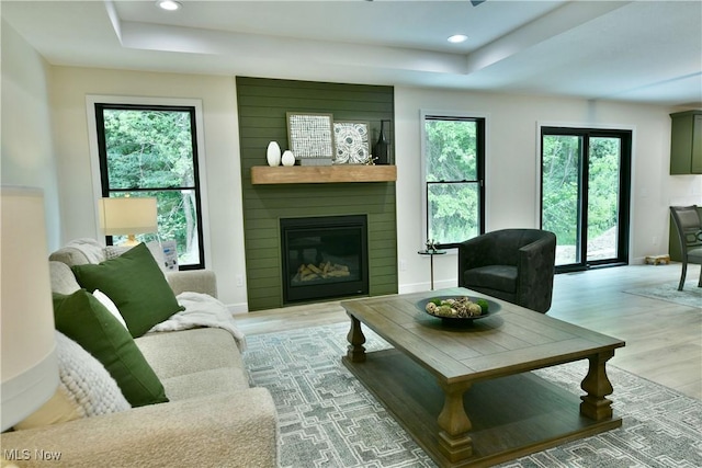 2320 Wilshire Dr, Cortland, OH 44410 - living area featuring a tray ceiling, light wood-style floors, a fireplace, and recessed lighting