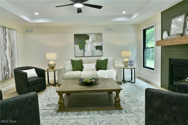 2320 Wilshire Dr, Cortland, OH 44410 - living area featuring a raised ceiling, wood finished floors, a ceiling fan, a glass covered fireplace, and recessed lighting