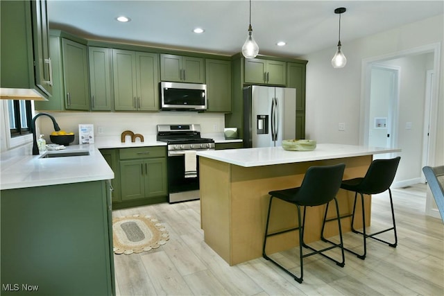 2320 Wilshire Dr, Cortland, OH 44410 - kitchen featuring appliances with stainless steel finishes, green cabinets, a breakfast bar area, light wood-style flooring, and pendant lighting