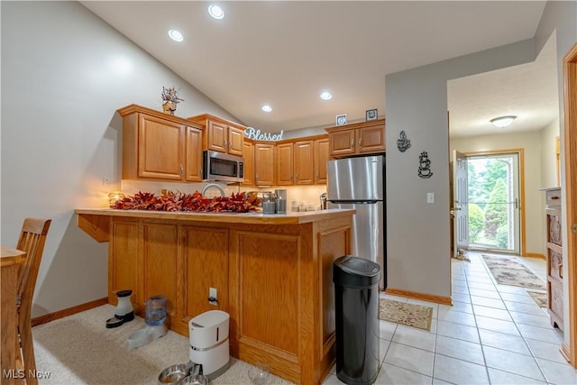 10393 Scotney Ave NW, North Canton, OH 44720 - kitchen featuring appliances with stainless steel finishes, a peninsula, recessed lighting, brown cabinets, and lofted ceiling