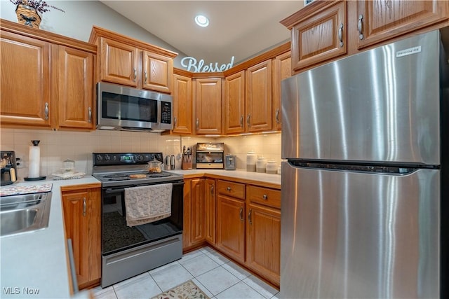 10393 Scotney Ave NW, North Canton, OH 44720 - kitchen with appliances with stainless steel finishes, light countertops, backsplash, vaulted ceiling, and light tile patterned floors