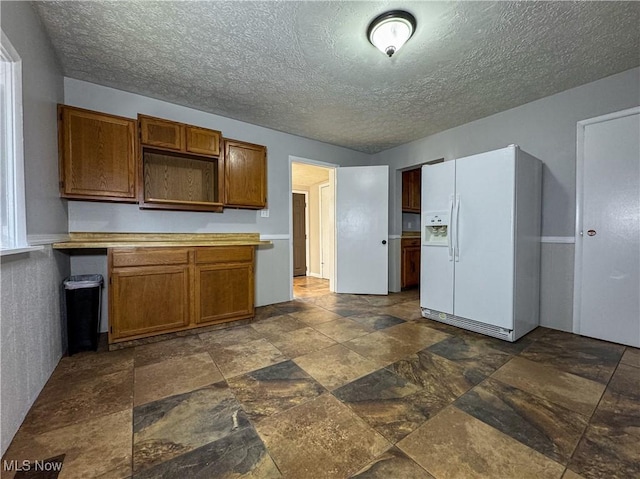 101 Ridgeway St, Struthers, OH 44471 - kitchen featuring white fridge with ice dispenser, stone tile flooring, a textured ceiling, brown cabinets, and light countertops